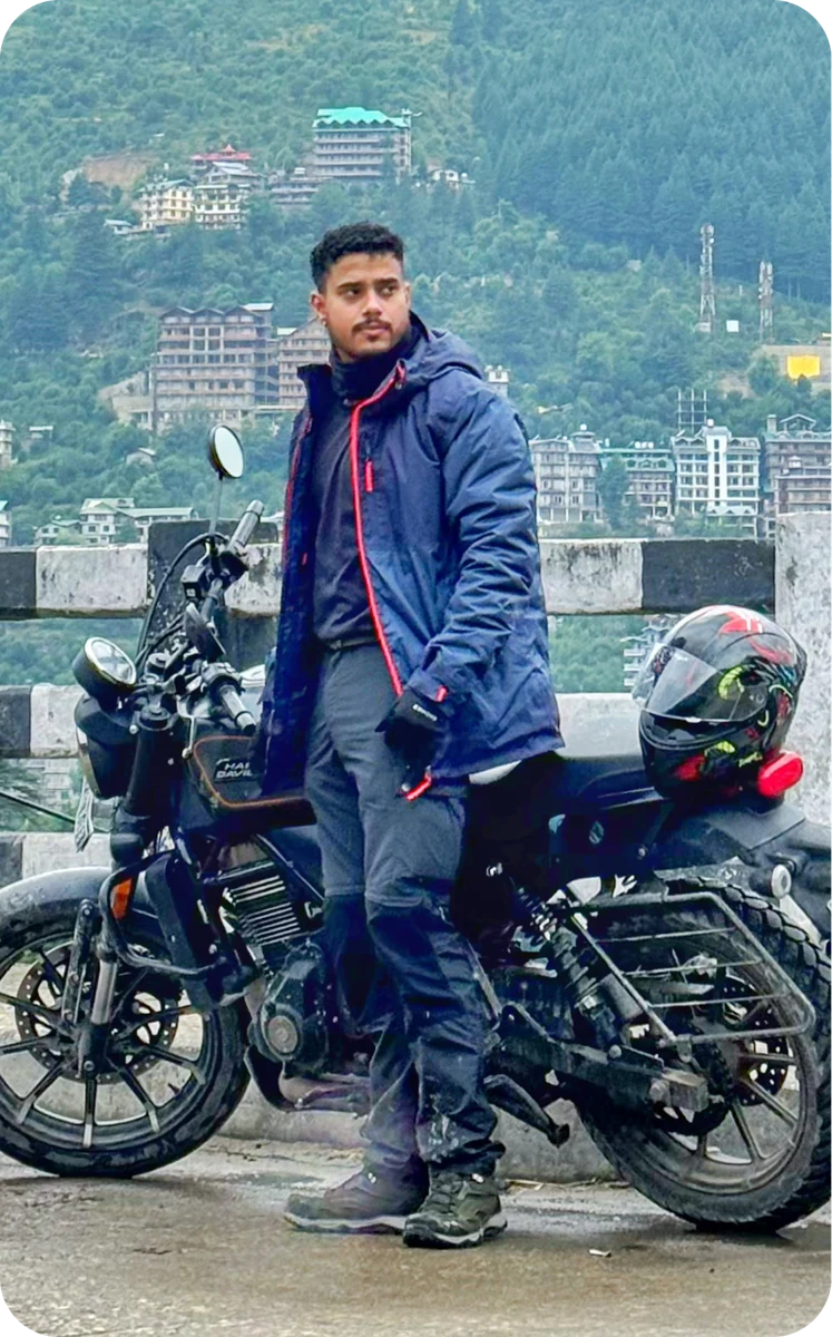 Shouvik beside his motorcycle in the mountains
